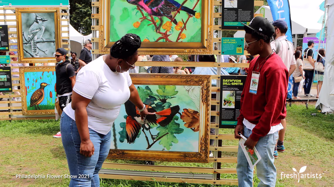 A group of people standing around a display of paintings